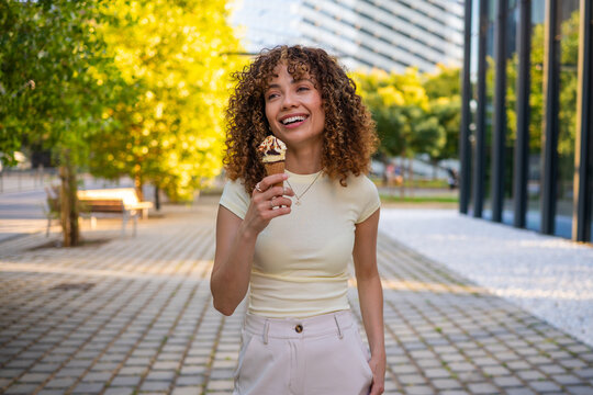 Woman smiling enjoying ice cream cone in city park