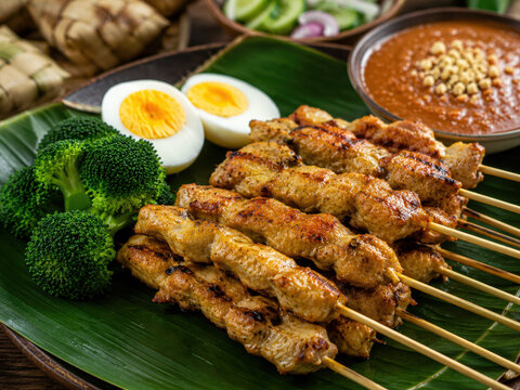 Chicken satay with peanut sauce, broccoli and boiled egg served on a banana leaf. Traditional Asian cuisine, balanced meal and healthy eating concept.