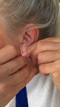 Close up macro shot of a woman wearing a blue tassel earring into her ear lobe.
