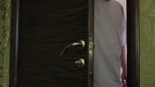 A man opens a door and enters a room, close-up