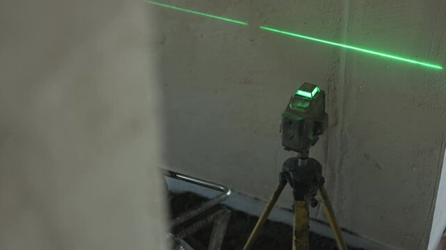 Green laser level projecting reference line on concrete wall