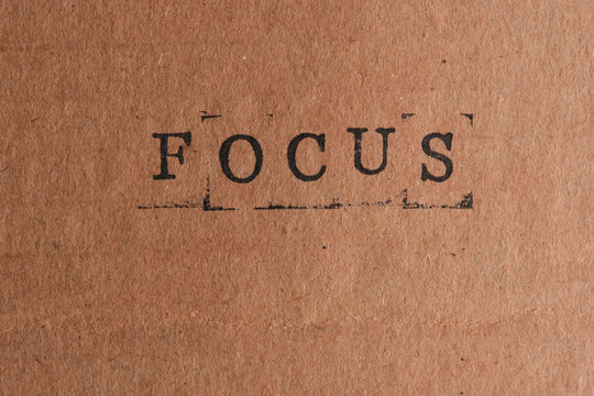Word FOCUS stamped in black ink across center textured brown craft paper background.