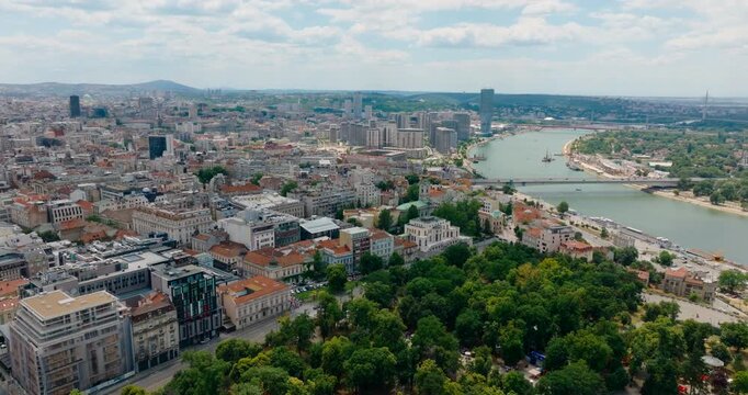 Establishing 4K drone shot zooming in toward the characteristic architecture of downtown Belgrade and central districts, with the Danube and Sava rivers visible on a sunny summer day before Expo 2027.