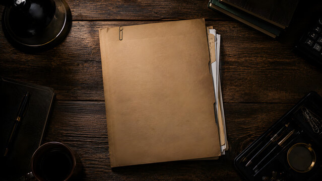 Vintage documents and office supplies arranged on a dark wooden surface featuring a paper folder and writing tools files manuscript