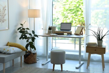 Fototapeta premium Workplace with laptop and stationery on table near window in office