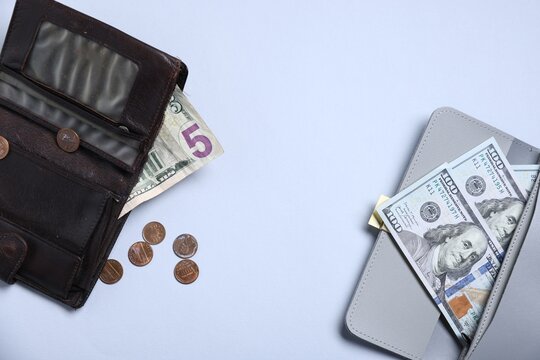 Contrast between poor and rich. Grey wallet with large bills and old one with small bill and coins on grey background, flat lay. Space for text