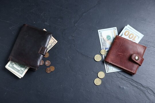 Contrast between poor and rich. Leather wallet with large bills and old one with small bills and coins on dark textured table, flat lay. Space for text