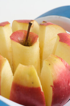 Macro close up shot freshly sliced red apple segments in kitchen slicer gadget.