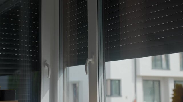 Roller shutters rise over large kitchen windows, allowing more daylight into the room. Concept of opening window coverings and sun control
