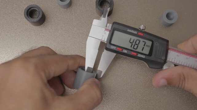 Engineer measuring plastic part with digital caliper