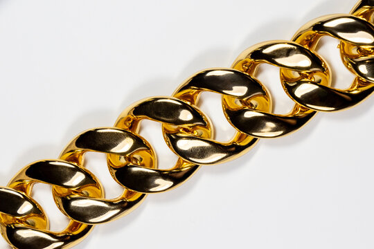 A chunky, highly polished gold curb chain with interlocking design features slightly flattened links