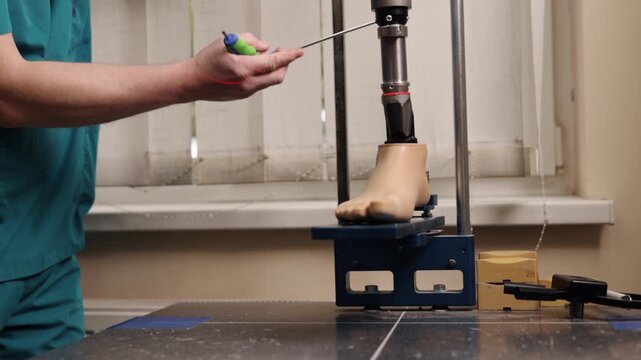 medical lab, alignment technician, prosthetic engineering. Laser-guided system is used by technician to carefully adjust prosthetic foot on controlled testing platform