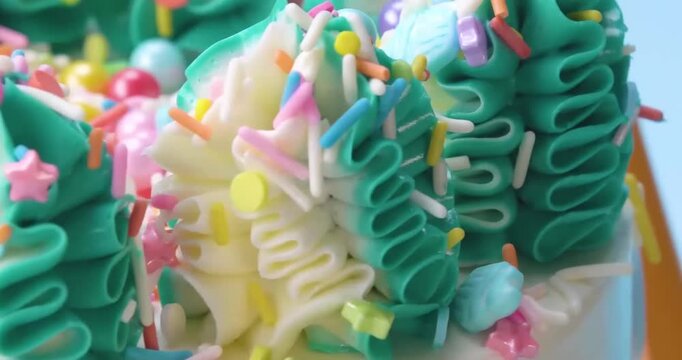Piped teal and white buttercream frosting with colorful sprinkles close-up