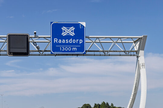 Raasdorp, Netherlands - Overhead metal gantry frame with blue traffic sign indicating Raasdorp highway interchange in 1300 meters.