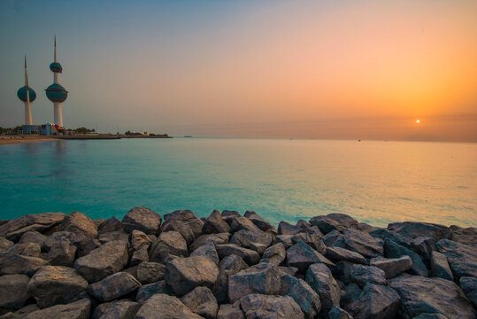 Kuwait Towers at sunset above a rocky breakwater on the Arabian Gulf coast