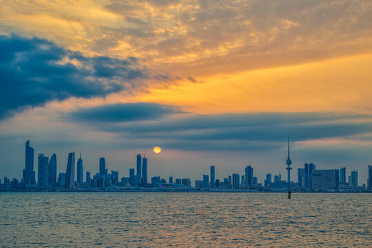 Kuwait City skyline at sunset with dramatic clouds seen across the bay