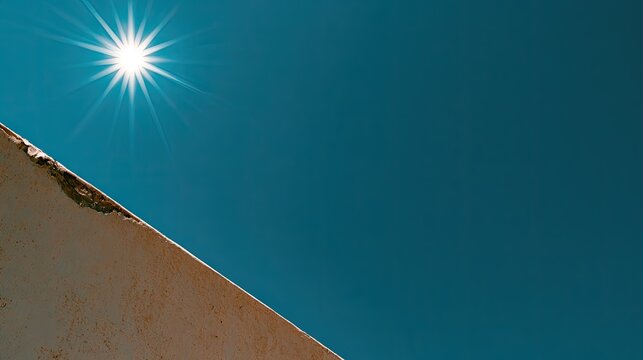 Bright sunbeams pierce a clear blue sky over a rough, textured surface