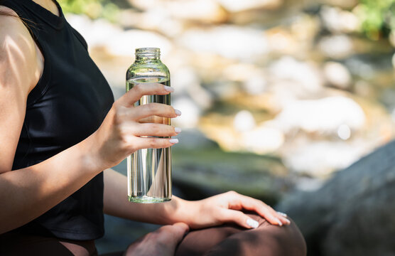 Fresh clean drinking water in a reusable glass bottle during an outdoor escape. Healthy hydration, sustainable lifestyle, plastic free choice and connection with nature.