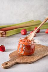 Fototapeta premium Homemade strawberry rhubarb jam in glass jar with wooden spoon