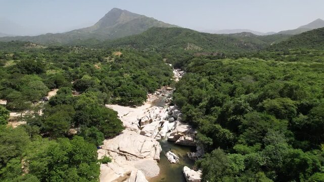 People swimming in a river in a green valley with mountains