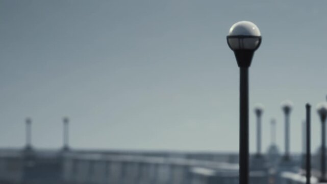 Lamp posts line a walkway next to a long wall. The sky looks gray, and the atmosphere appears dim. The scene shows the structure and the light sources in a city setting.