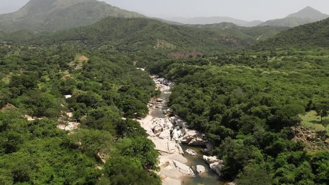 Aerial view of river flowing through green forested mountains