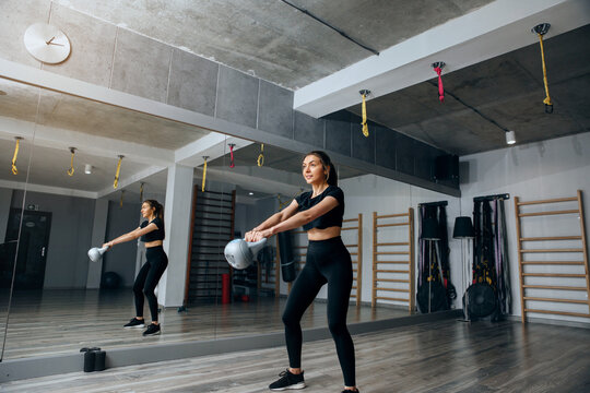 Woman exercising with kettlebell in gym during daytime
