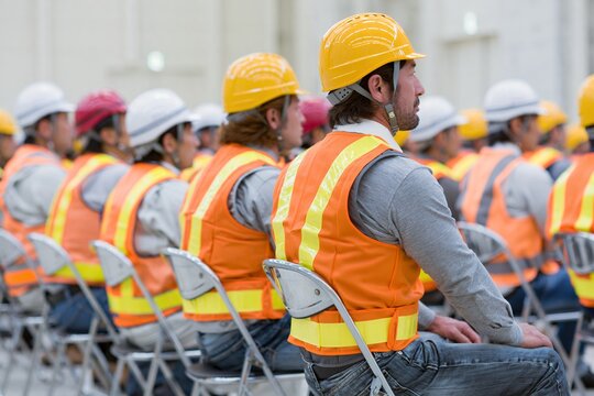 建設現場で安全講習を熱心に聴講する複数の男性作業員