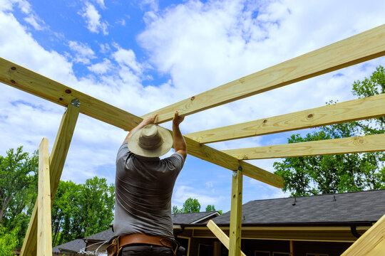 Wood worker is assembling wooden beams for structure in backyard