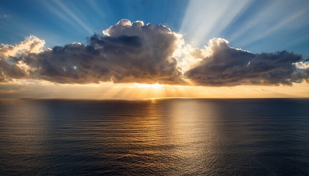 sun rays breaking through dramatic clouds over calm ocean horizon creating golden light reflection