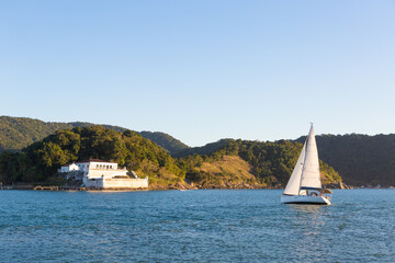 Fototapeta premium Sailboat Sailing Along the Coast of Santos, Brazil