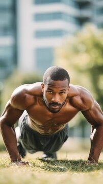 Muscular male athlete working out with push ups outside, demonstrating dedication to a healthy lifestyle. Urban fitness and outdoor exercise concept with modern city buildings in the background