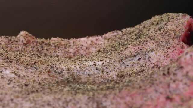 A detailed close-up shot of a fresh raw beef steak, seasoned with black pepper and sea salt, ready for a gourmet barbecue. The marbling and texture of the meat are visible in cinematic lighting, perfe