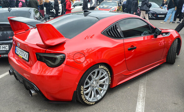Bright red Scion FR-S sports coupe, prominently showing its aggressive front fascia, modern projector headlights, silver brand emblem, and a black front splitter