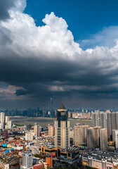Obraz premium Aerial view of Wuhan city skyline under a massive cumulonimbus cloud. The Yangtze River flows through the dense urban landscape with large bridges visible. Dramatic summer weather over the metropolis.