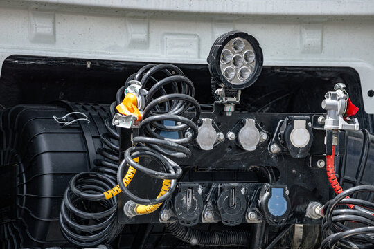 Semi truck cabin back wall with trailer connection lines. Commercial vehicle air brake spiral hoses and electrical sockets panel closeup view with industrial transport technical details.