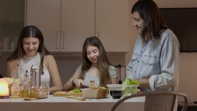 Single father and his two teenage daughters enjoying a moment of connection while cooking a healthy meal together in their modern kitchen, fostering family bonds