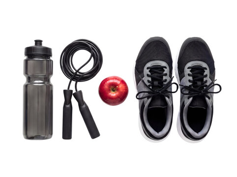Overhead view of fitness essentials a sleek metal water bottle, a jump rope, a vibrant red apple, and athletic sneakers, set against a clean white background.