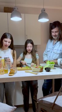 Vertical shot of a father having fun with his teenage daughters while cooking  for dinner