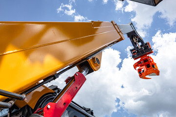 Telehandler telescopic boom arm with hydraulic lift cylinder. Modern construction machinery yellow crane mechanism section against sky background with industrial heavy duty vehicle details. © NastyaPhoto