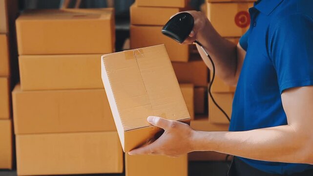 Warehouse worker scanning a cardboard box with a barcode scanner for inventory management and shipping logistics in a distribution center