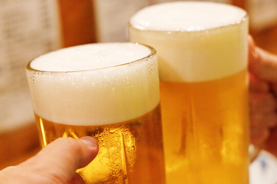居酒屋でビールジョッキを合わせて乾杯する手元