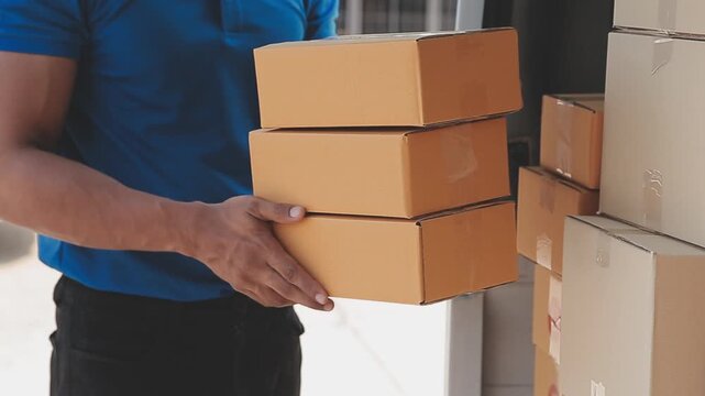 Delivery man holding a stack of cardboard boxes while unloading from a delivery van for shipping and logistics service