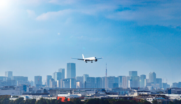 東京のウォーターフロント都市群をバックに着陸態勢に入る旅客機