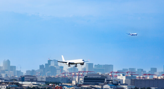 東京のウォーターフロント都市群をバックに着陸態勢に入る旅客機