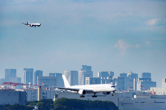 東京のウォーターフロント都市群をバックに着陸態勢に入る旅客機