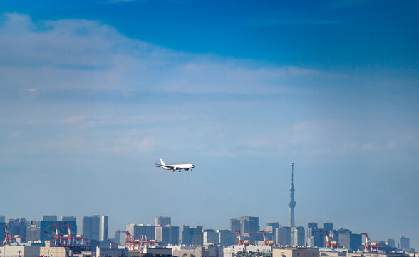 東京のウォーターフロント都市群をバックに着陸態勢に入る旅客機