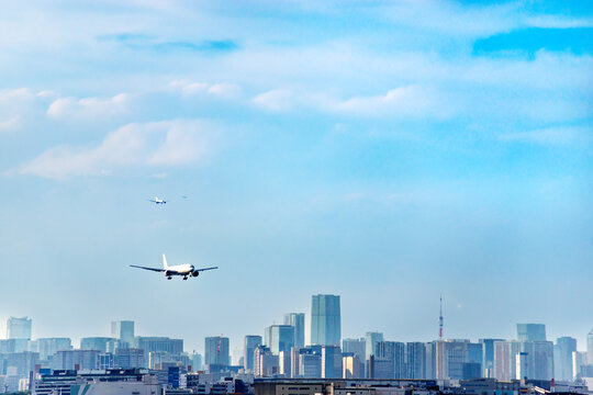 東京のウォーターフロント都市群をバックに着陸態勢に入る旅客機