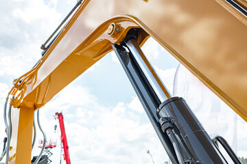 Telehandler telescopic boom arm raised above yellow cabin roof. Modern crane machinery mechanism with pallet forks attachment and heavy duty industrial transport vehicle technical details. © NastyaPhoto