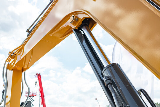 Telehandler telescopic boom arm raised above yellow cabin roof. Modern crane machinery mechanism with pallet forks attachment and heavy duty industrial transport vehicle technical details.